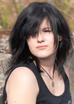 Punk emo girl, young adult with black hair and eyeliner, close-up, looking away, standing, outdoors, vetical