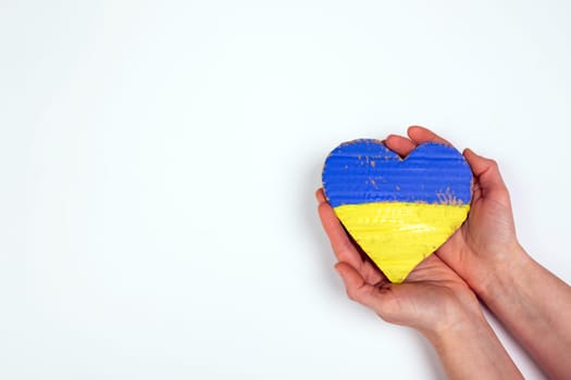 Heart shaped flag of Ukraine in female hands. The concept of solidarity with the citizens of Ukraine.