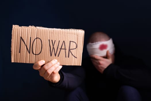 Wounded man holding placard with No war text. Stop war, russian aggression, freedom to Ukraine concept.