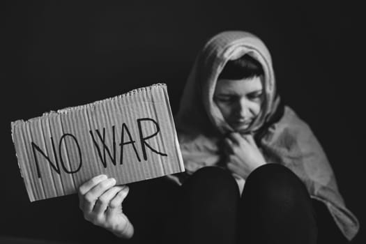 Ukrainian refugee holding placard with No war text. Evacuation of civilians. Freedom to Ukraine concept.