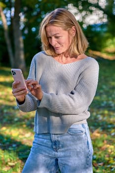 A woman in a park in the summer speaks during a video call on the phone. High quality photo