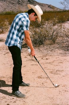 Young boy in natural terrain desert golfing
