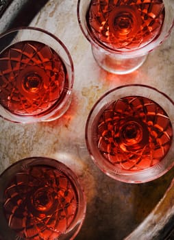 Cherry liqueur in vintage crystal glasses over dark background