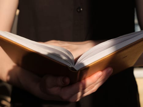 Book in hands close up in daylight. The person is reading an interesting book
