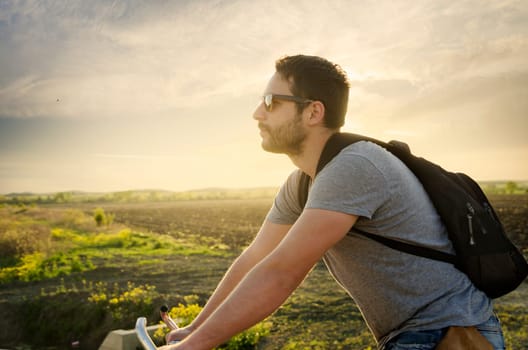 Man riding a bicycle in nature at sunset