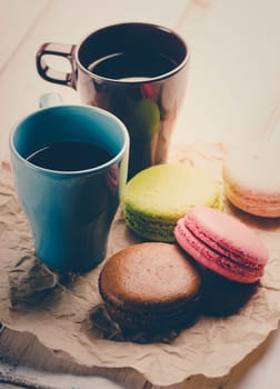 Two cup of coffee and colorful macaroons. Retro filter.