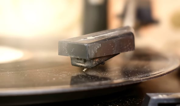Close-up of the cartridge of an old, ruined turntable reading a 33 rpm vinyl record. Analog sound reproduction in stereo high fidelity
