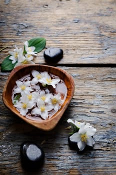Spa concept. Jasmin flower and spa stones on wooden table.