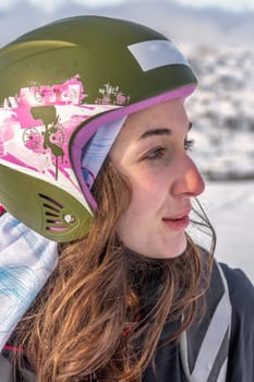 Women with brown standing on top of a mountain, wearing ski helmet and ski wear, serious facial expression, looking at ski slope, stryn norway close-up, vertical