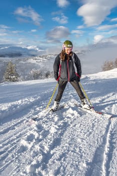 Women with brown hair taking a break, skiing in stryn norway, standing confident on top of a mountain, looking down, smiling, horizontal