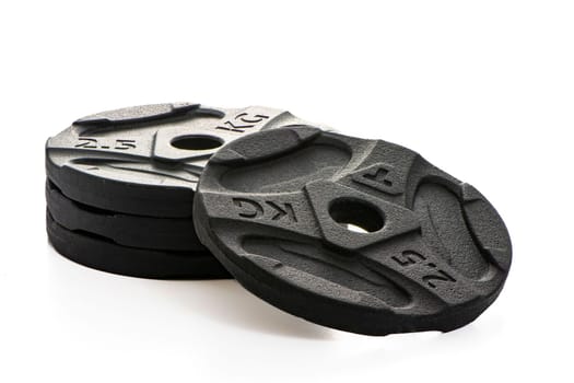 Four black metal pancakes of 2.5 kg each lie on a white isolated background. High quality photo