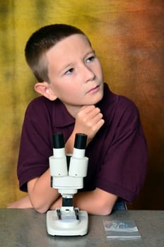 Young boy scientist with microscope examining a sample