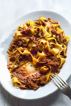 close up of plate of rustic italian pappardelle pasta in bolognese sauce