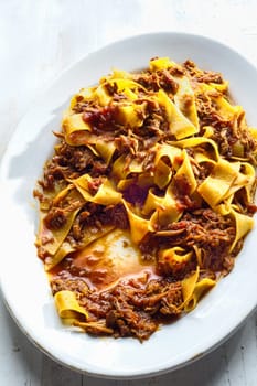 close up of plate of rustic italian pappardelle pasta in bolognese sauce