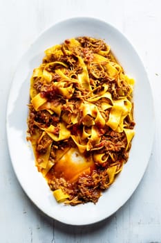 close up of plate of rustic italian pappardelle pasta in bolognese sauce