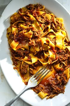 close up of plate of rustic italian pappardelle pasta in bolognese sauce