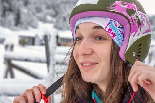 Woman with brown hair smiling while adjusting her ski helmet, getting ready for skiing in ski centre stryn, norway, close-up, horizontal