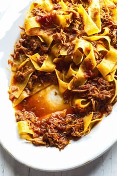 close up of plate of rustic italian pappardelle pasta in bolognese sauce
