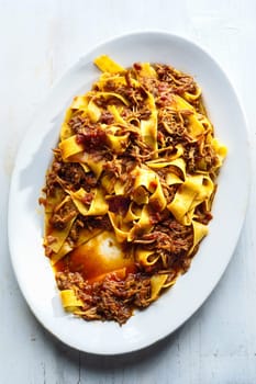 close up of plate of rustic italian pappardelle pasta in bolognese sauce