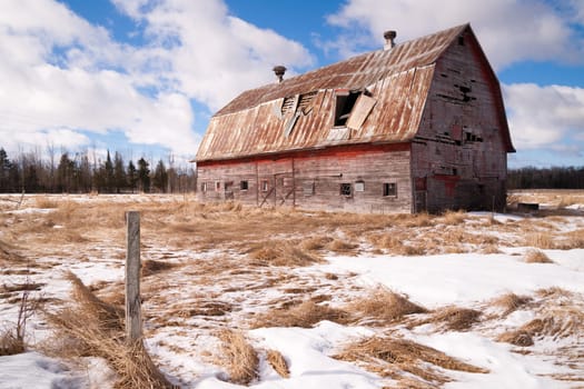 Fresh snow sits on the ground around an old barn