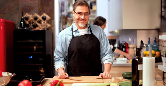 Caucasian man cooking in the kitchen at home. Mature age, middle age, mid adult white man in 50s.