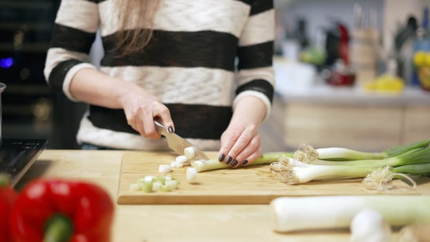 Woman cooking in kitchen at home, healthy eating. Close up of hands, slicing.