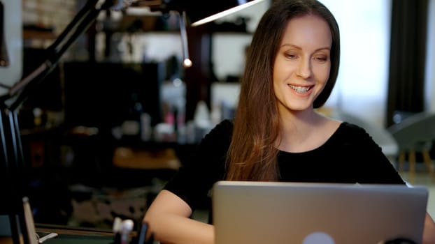 Happy woman working in home office with laptop computer, blogger writing online, browsing internet, smiling.
