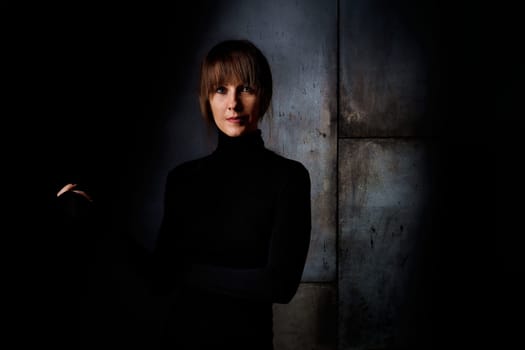Beauty portrait of attractive young woman looking at camera, serious facial expression. Dark background.
