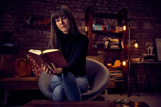young 30s woman reading a book at home relaxing.