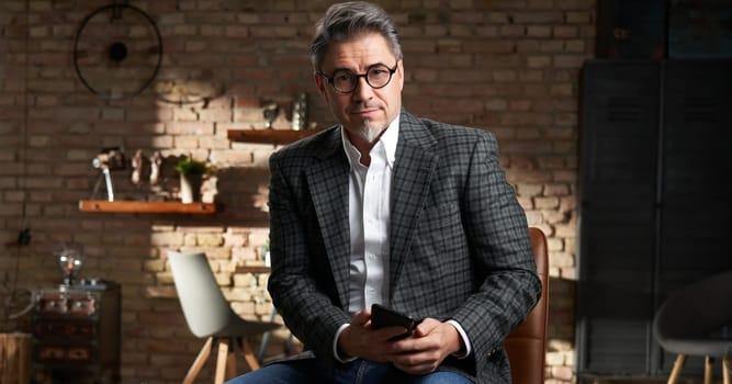 Stay at home - Smart looking older business man in home office using mobile phone for work.