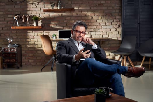 Man working in home office using phone the browse the internet.