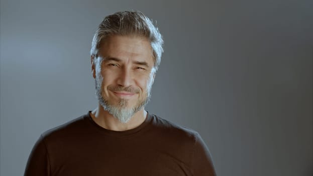 Portrait of happy older white man on gray background, smiling, copy space.