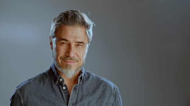 Portrait of happy older white man, beard gray hair, smiling. Copy space for text gray background
