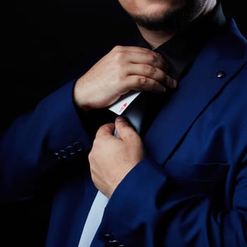 Magician illusionist showing performing card trick. Close up of hand and poker cards on black background.
