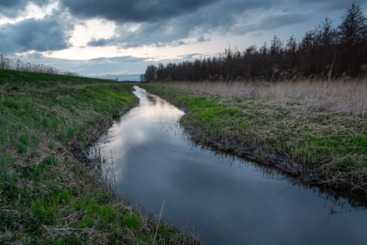 Uherka river in eastern Poland and cloudy sky, spring evening