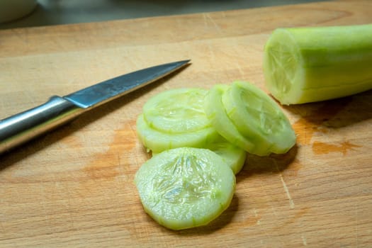 Peeled green cucumber, sliced with a silver knife