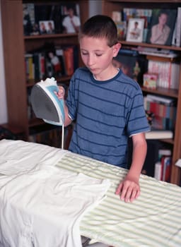 Young boy ironing a shirt on an ironing board