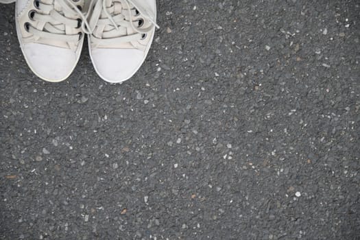 Go new ways. White shoes on the asphalt of a gray street.