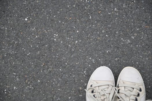 Go new ways. White shoes on the asphalt of a gray street.