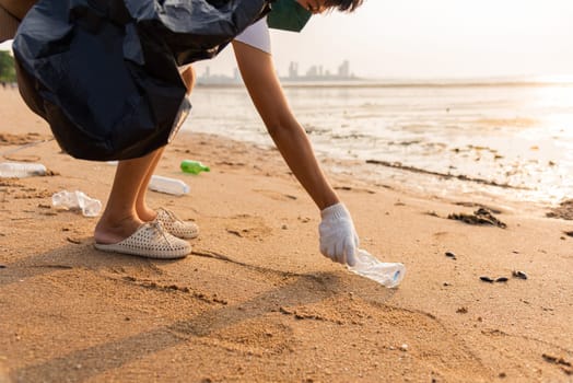 Volunteer woman picking plastic bottle into trash plastic bag black for cleaning the beach, female clean up garbage, Ecology concept and World Environment Day, Save earth concept