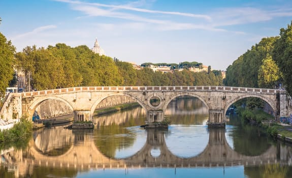 ROME, ITALY - CIRCA AUGUST 2020: Bridge on Tiber river with Vatican Basilica cupola in background and sunrise light.