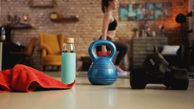 Fitness training at home. Young woman doing leg workout, exercising in living room. Focus on fitness equipment. Stay at home and stay fit and healthy.