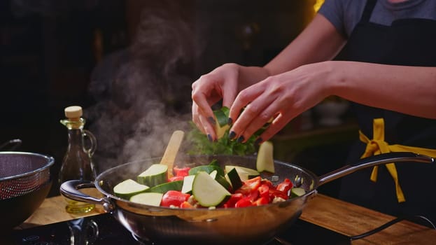 Woman cooking frying in wok pan on kitchen table.