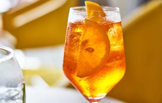 Glass of cold refreshing aperol spritz cocktail on table in summer.
