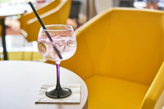 Glass of cold refreshing gin tonic cocktail on table in summer.