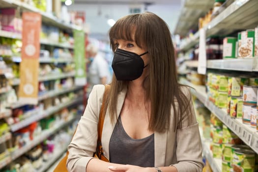 Young woman in face mask shopping in grocery store supermarket.