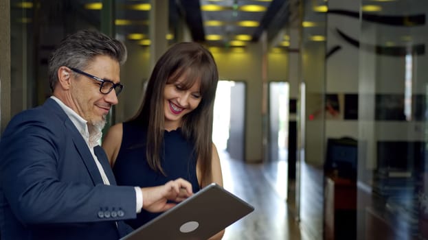 Happy business people working with tablet in office. Businessman and businesswoman teamworking.