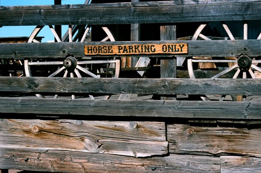 Old weather worn wooden fence with horse parking only sign