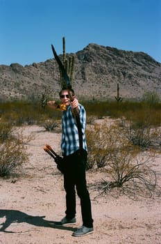 Young man shooting a bow and arrow in the desert