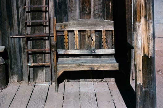 Old rustic wooden bench on a wooden sidewalk, bucolic